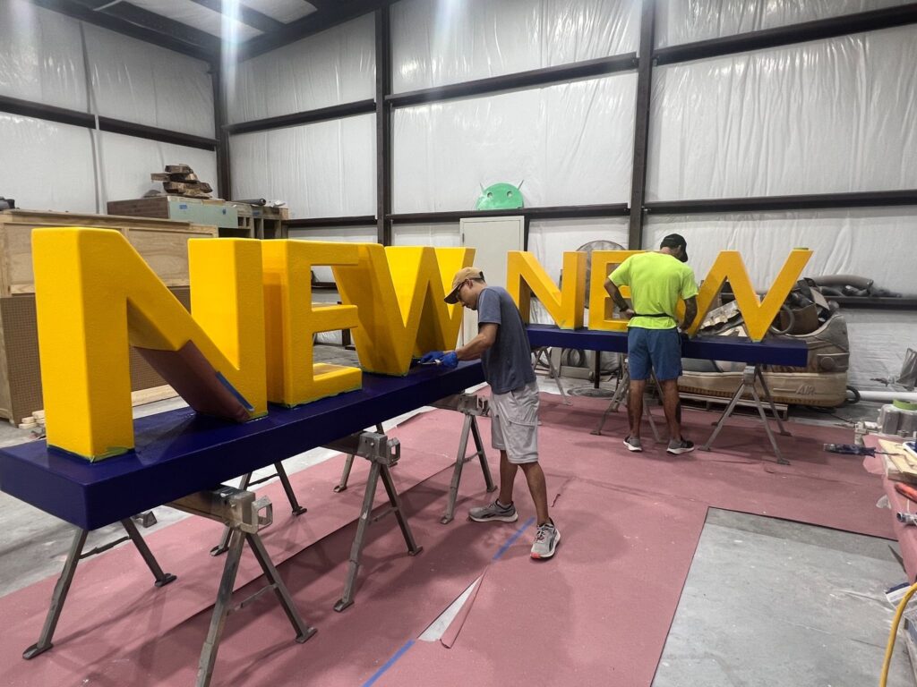 Smash Design artists sculpting huge foam letters in our Texas studio